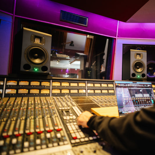 Person operating a mixing console in a studio setting with TYPE 07 ACORE monitors